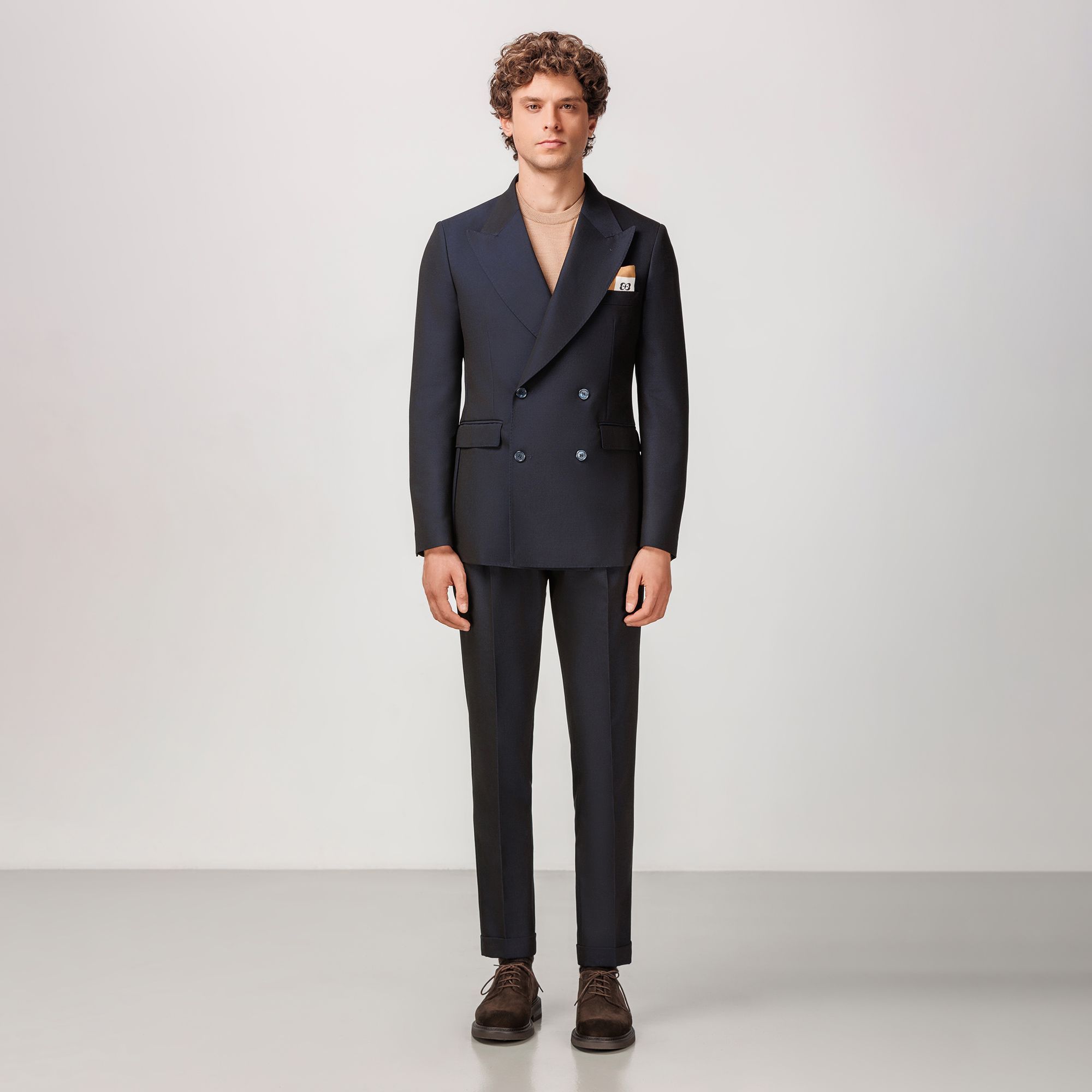 Navy double-breasted suit by Elio Evan, crafted from a sustainable lyocell and virgin wool gabardine blend with peak lapels and single pleated trousers.