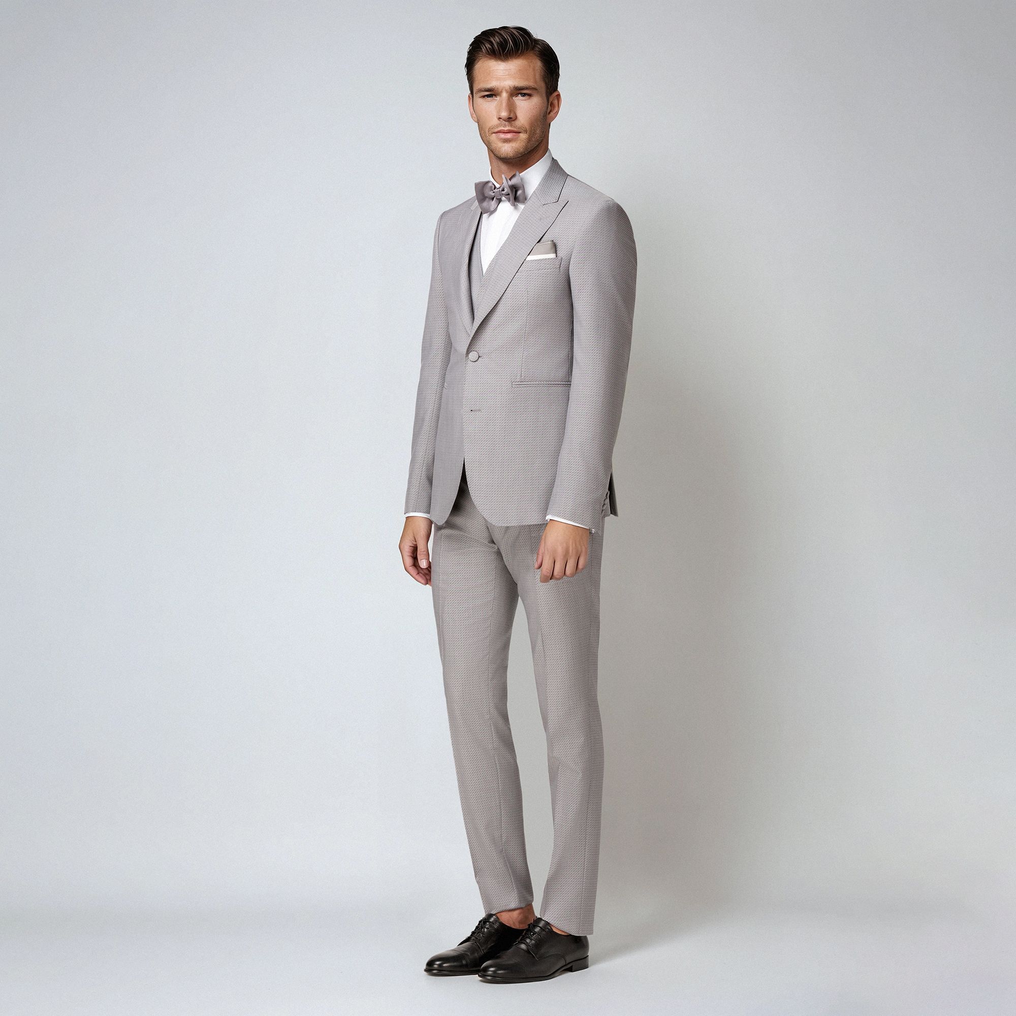 Abito tre pezzi in jacquard lana-seta grigio. Giacca monopetto con rever a lancia, bottoni rivestiti e costruzione sartoriale. Made in Italy.