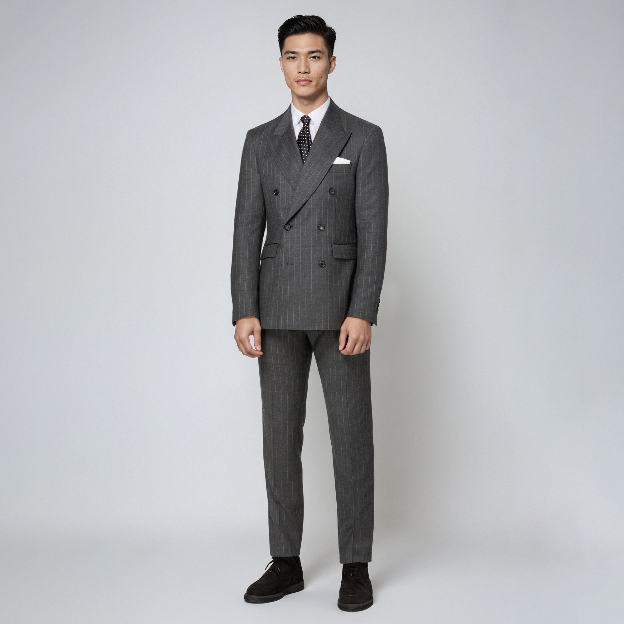 Uomo con total look Elio Evan: abito doppiopetto gessato grigio in lana, camicia bianca e cravatta.