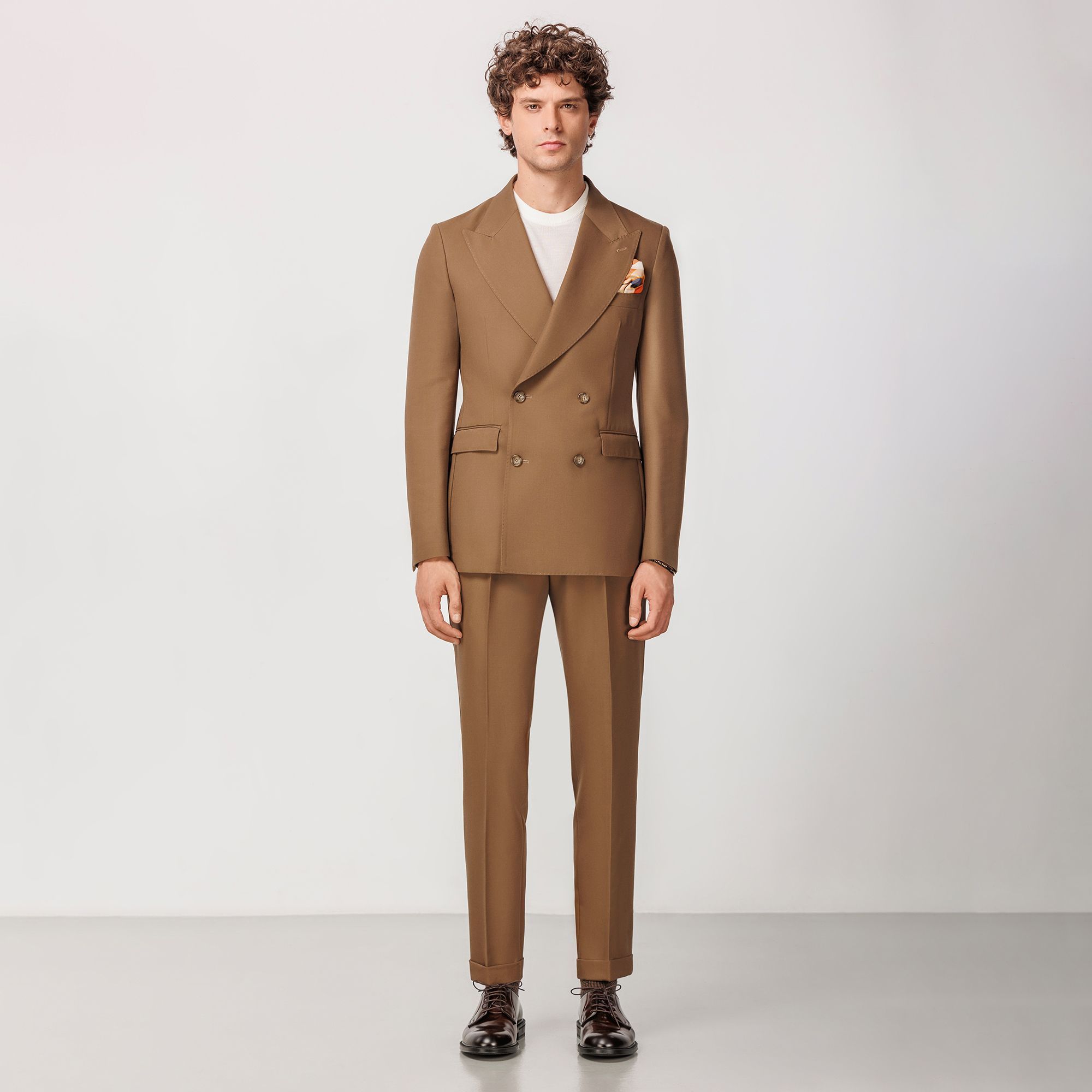 Camel double-breasted suit by Elio Evan, crafted from a sustainable lyocell and virgin wool gabardine blend with peak lapels and single pleated trousers.